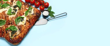 Delicious Italian pie with mozzarella and pesto sauce on light blue background with space for text