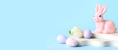Empty podiums with Easter eggs, bunny and tulip flower on blue background with space for text