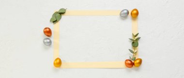 Composition with blank frame, Easter eggs and eucalyptus branches on light background