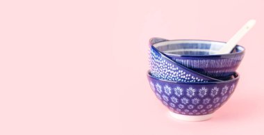 Chinese bowls with spoon on pink background with space for text
