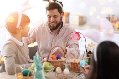 Young father with his little son painting Easter eggs in kitchen