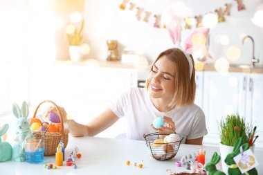 Güzel bir kadın evde paskalya yumurtası boyuyor.