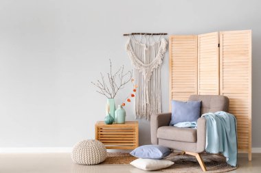 Interior of living room with armchair and tree branches in vases