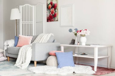 Interior of living room with sofa and flowers in vases