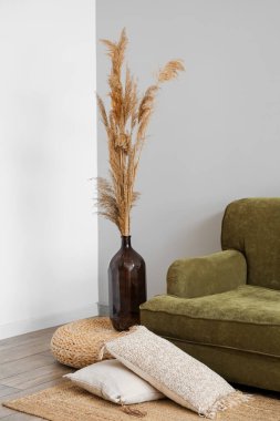 Vase with pampas grass on rattan pouf in living room