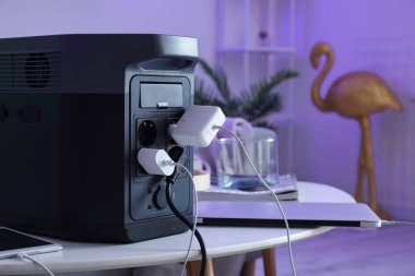 Portable power station charging devices on table in living room, closeup
