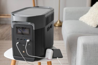 Portable power station charging devices on table in living room, closeup