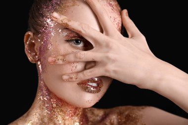 Young woman with glitter makeup on black background, closeup