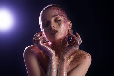Beautiful young woman with glitter makeup on dark background, closeup