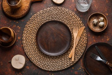 Beautiful table setting with wooden plates and quail eggs on brown grunge background