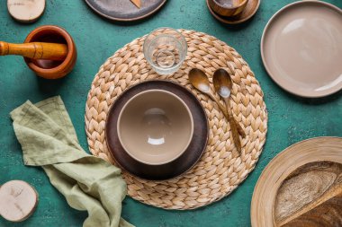 Beautiful table setting with plates, bowl and glass of water on green grunge background