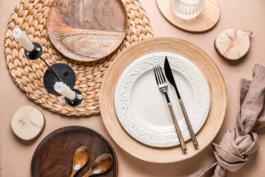 Beautiful table setting with plates, candles and cutlery on beige grunge background