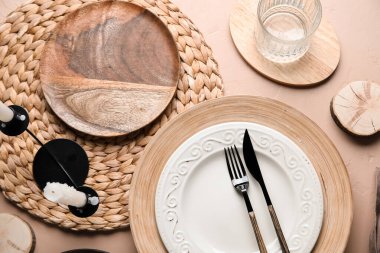 Beautiful table setting with plates, candles and glass of water on beige grunge background