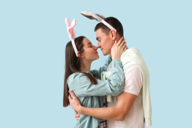 Happy young couple in bunny ears hugging on blue background. Easter celebration