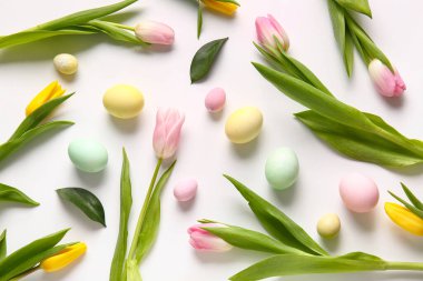 Composition with beautiful tulip flowers and Easter eggs on white background