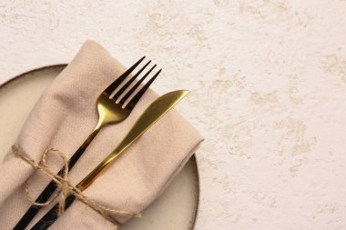 Plate with napkin, fork and knife on white grunge background