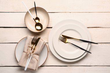 Plates with set of cutlery on white wooden background