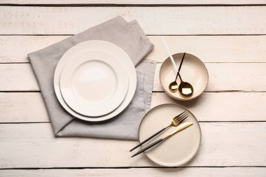 Plates with set of cutlery on white wooden background