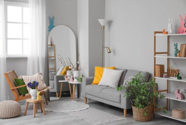 Interior of living room with Easter decor, sofa and mirror