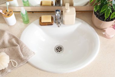 White sink and cosmetic products on table in room
