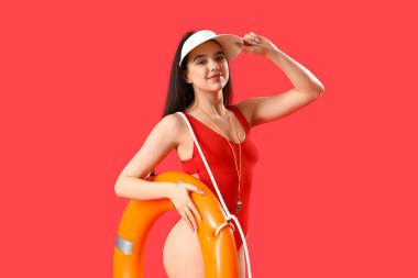 Female lifeguard with ring buoy on red background