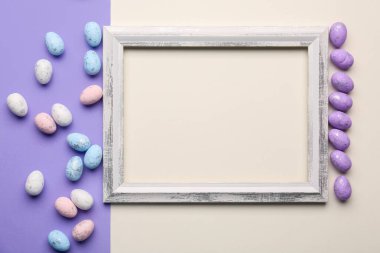 Blank wooden frame with painted Easter eggs on white and lilac background