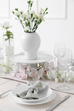 Beautiful table setting for International Women's Day celebration with eustoma and orchid flowers in light room