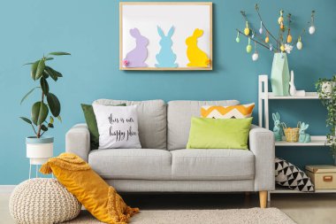 Interior of living room with Easter decor, sofa and shelving unit