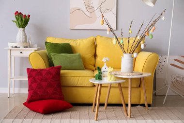 Interior of living room with Easter decor, yellow sofa and tables
