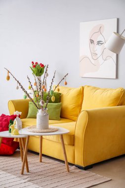 Interior of living room with Easter decor, yellow sofa and tables