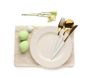 Table setting with Easter eggs, cutlery and eustoma flowers isolated on white background