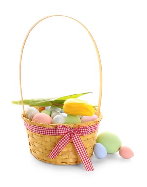 Basket with painted Easter eggs and tulip flower on white background