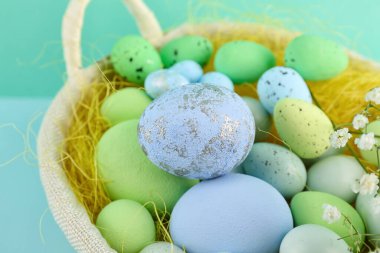 Basket with beautiful Easter eggs on color background, closeup