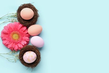 Composition with Easter eggs, nests and beautiful flowers on color background