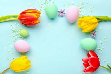 Composition with Easter eggs, spring flowers and confetti on color background, closeup