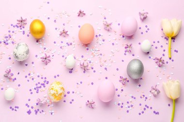 Composition with beautiful Easter eggs, spring flowers and confetti on color background