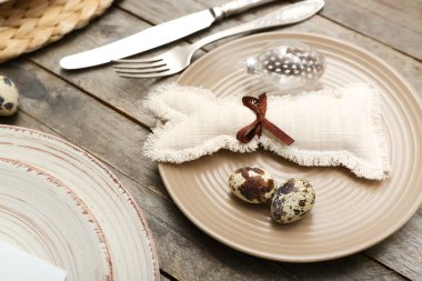 Plate with Easter eggs and bunny on wooden background, closeup