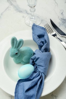 Table setting with Easter egg and bunny on white marble background