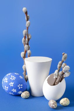 Composition with podium, willow branches and Easter eggs on color background