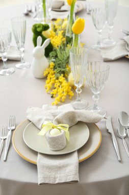 Festive table setting with painted eggs and flowers served for Easter celebration