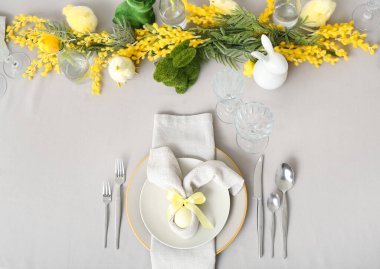 Festive table setting with painted egg and flowers served for Easter celebration