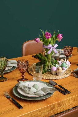 Festive dining table with painted eggs and tulip flowers served for Easter celebration