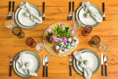 Festive table setting with painted eggs and flowers served for Easter celebration