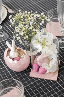 Festive table setting with painted eggs, bunnies and flowers served for Easter celebration