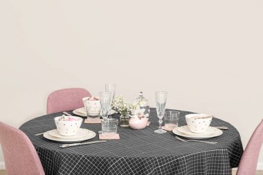 Festive dining table with gypsophila flowers served for Easter celebration near white wall