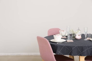 Festive dining table with gypsophila flowers served for Easter celebration near white wall