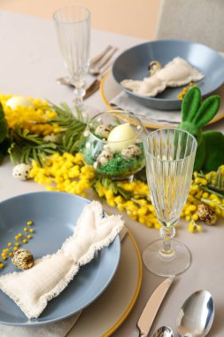 Bunnies, eggs and mimosa flowers on table served for Easter celebration