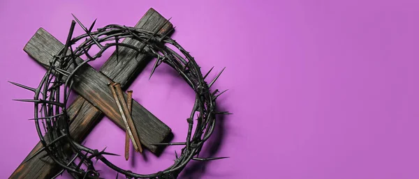 Crown of thorns, wooden cross and nails on purple background with space for text