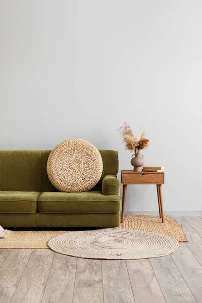 Interior of living room with green sofa and pampas grass in vase