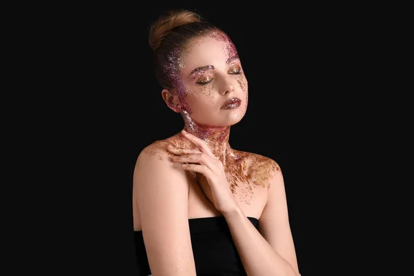 Young woman with glitter makeup on black background
